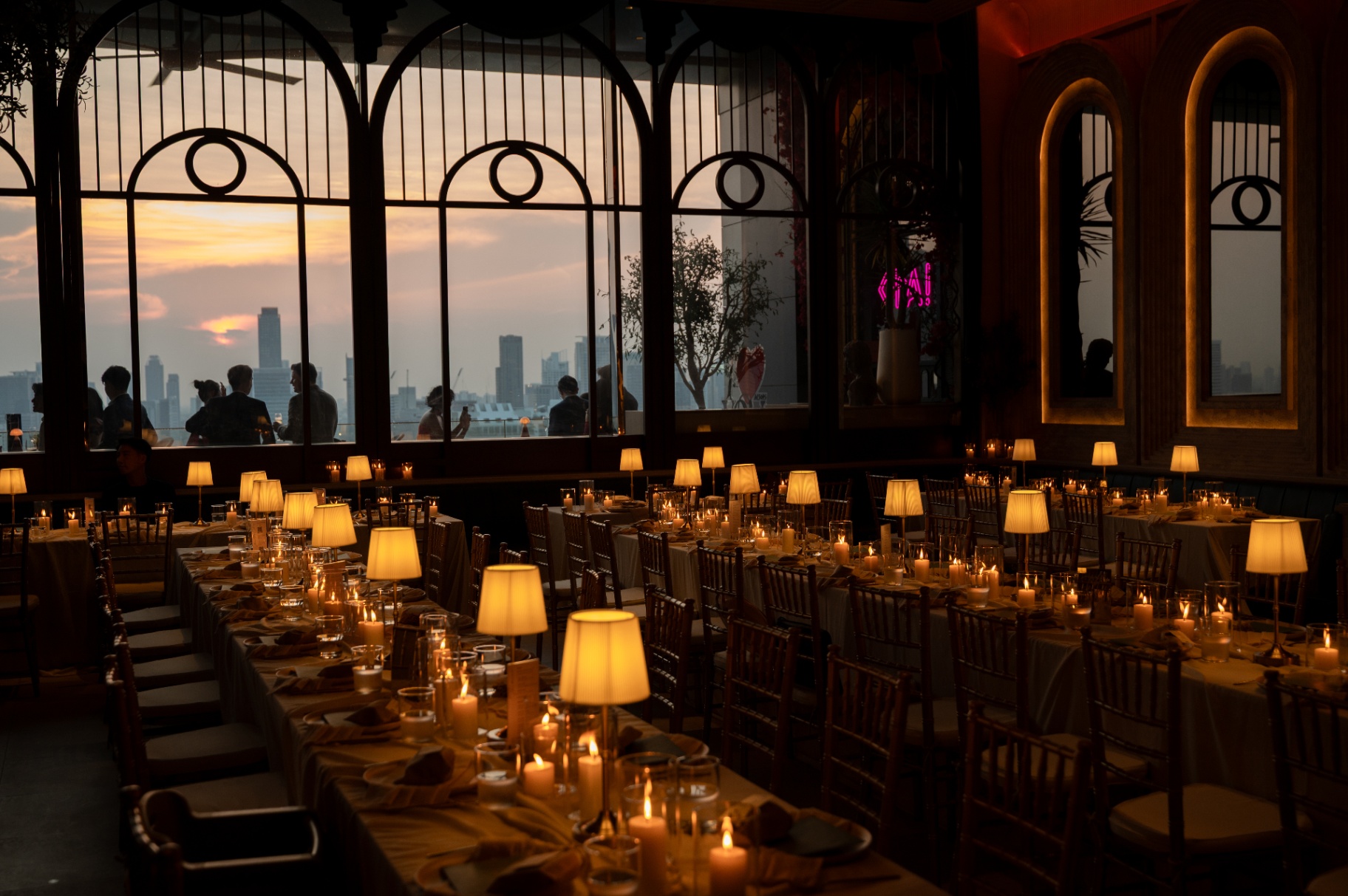 Long candlelit reception tables at sunset overlooking the Bangkok skyline