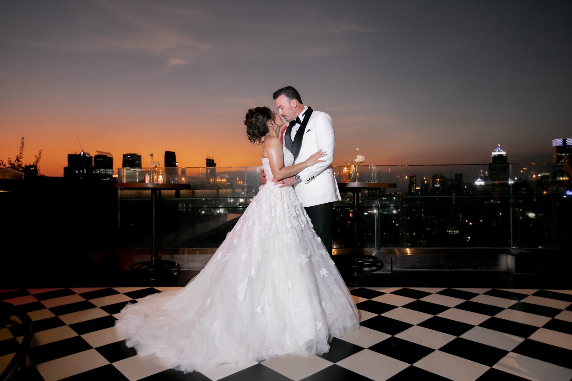Bride and groom embracing on the Aesops rooftop terrace at sunset with the Bangkok skyline behind