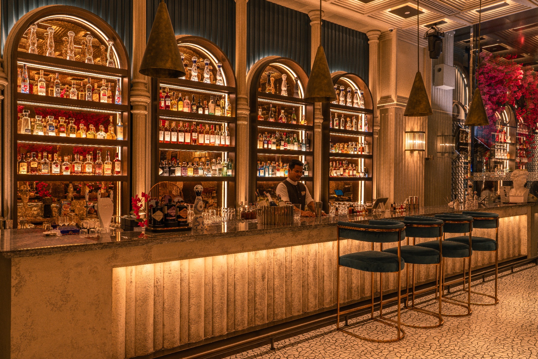 Arched marble bar lined with spirits and velvet stools
